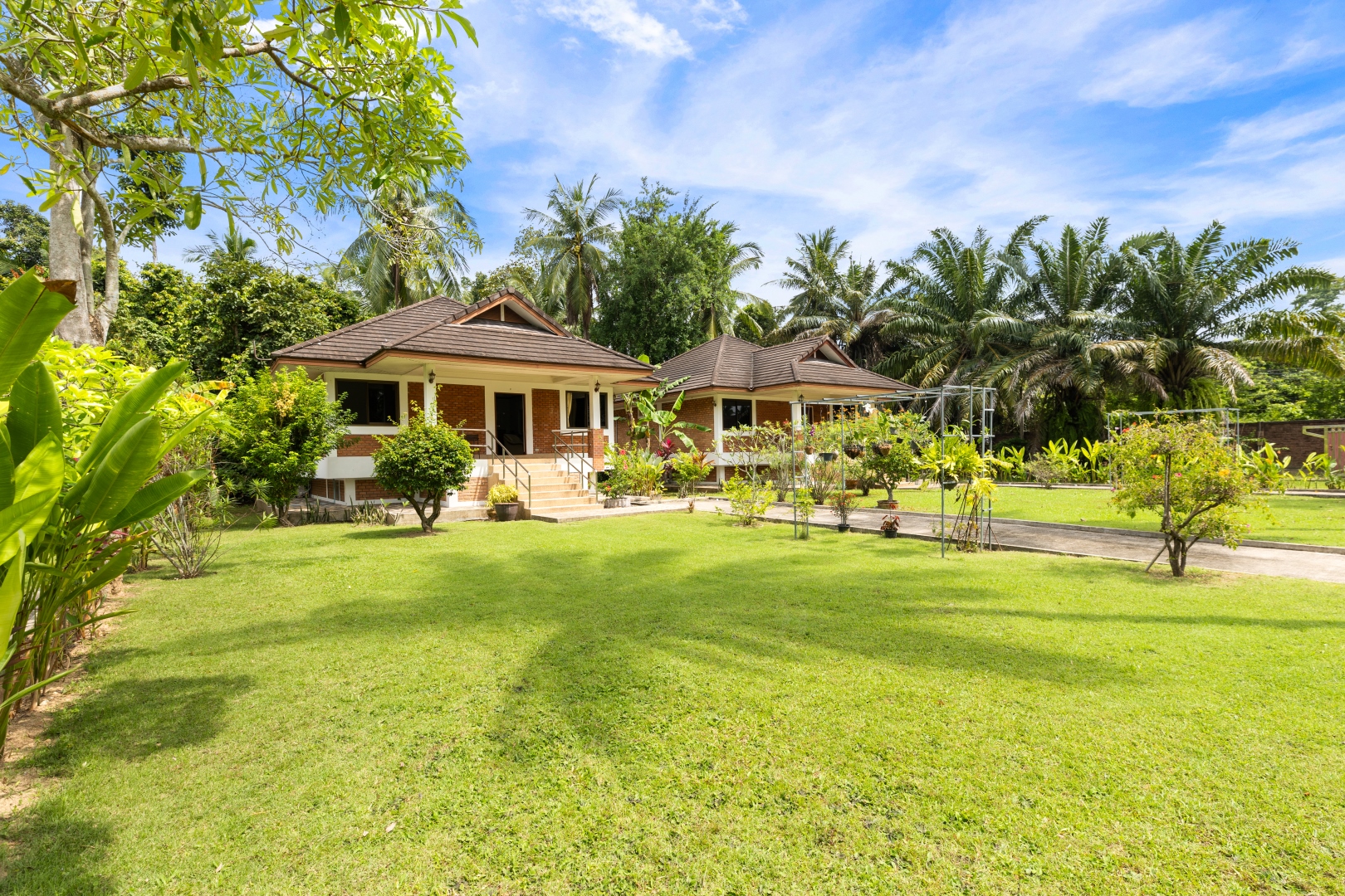 A thatched bungalow framed by palms and tropical garden